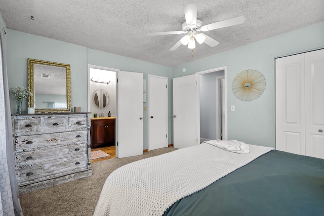 bedroom featuring a textured ceiling, connected bathroom, carpet flooring, visible vents, and a closet