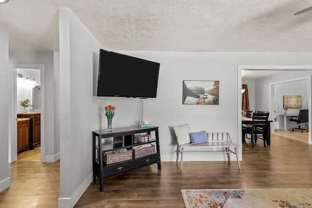 interior space with a textured ceiling, wood finished floors, and baseboards