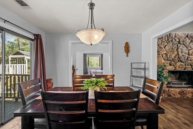 dining room featuring a fireplace, wood finished floors, and visible vents