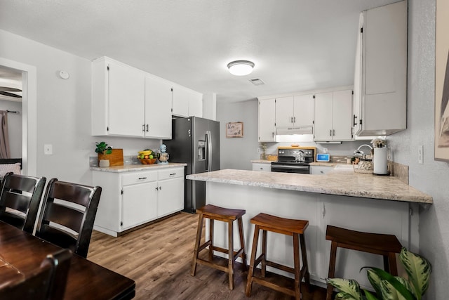 kitchen featuring light countertops, wood finished floors, a peninsula, black / electric stove, and stainless steel fridge with ice dispenser