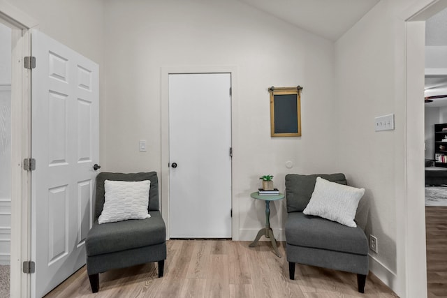 living area with baseboards, wood finished floors, and vaulted ceiling