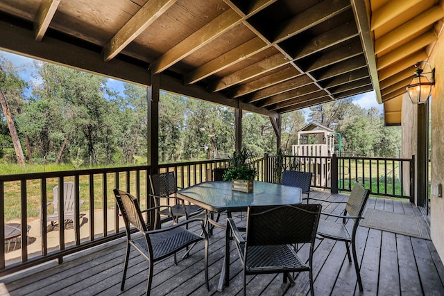 wooden terrace with outdoor dining area and a playground