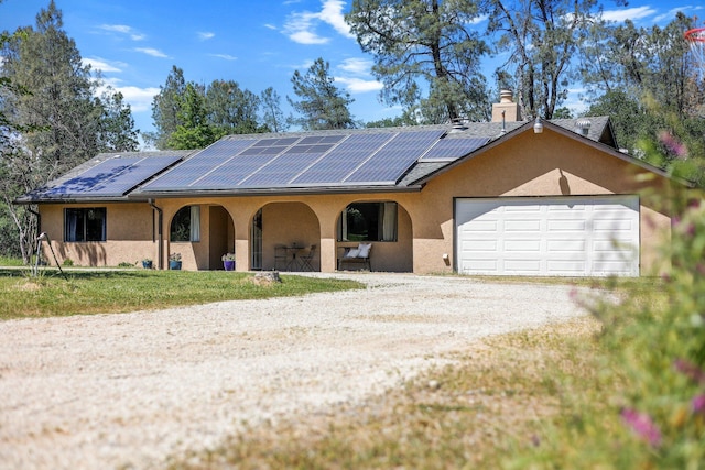 view of front of home featuring a porch, stucco siding, a garage, roof mounted solar panels, and driveway