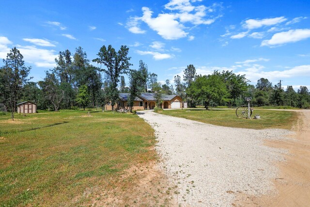 view of front of home with gravel driveway, a storage unit, an outbuilding, roof mounted solar panels, and a front lawn