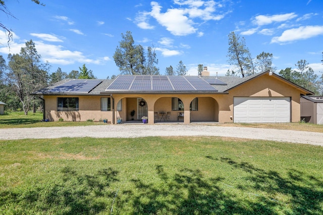 single story home featuring a porch, gravel driveway, stucco siding, roof mounted solar panels, and a front lawn