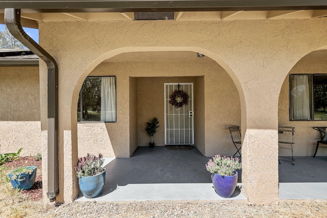 entrance to property with a patio and stucco siding