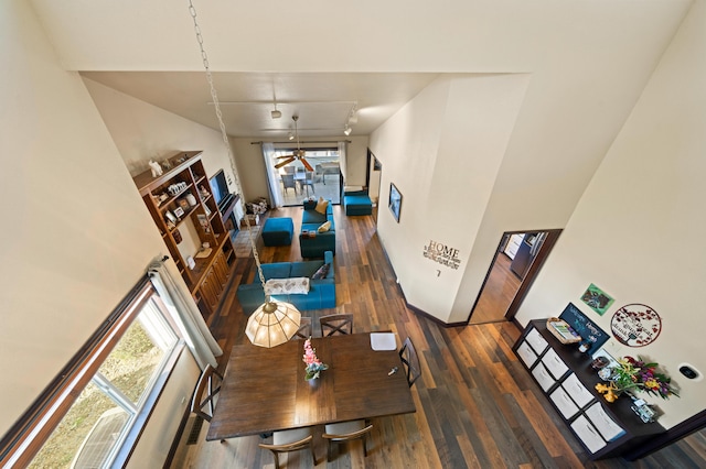 living area with wood finished floors, a healthy amount of sunlight, and a towering ceiling