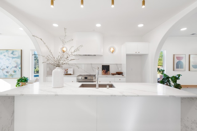 kitchen featuring white cabinets, a large island with sink, a sink, modern cabinets, and light stone counters