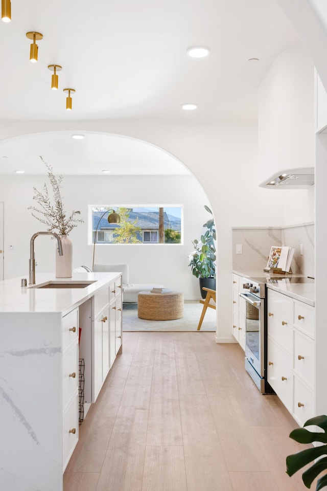 bar featuring arched walkways, a sink, stainless steel range with electric cooktop, recessed lighting, and light wood-style floors