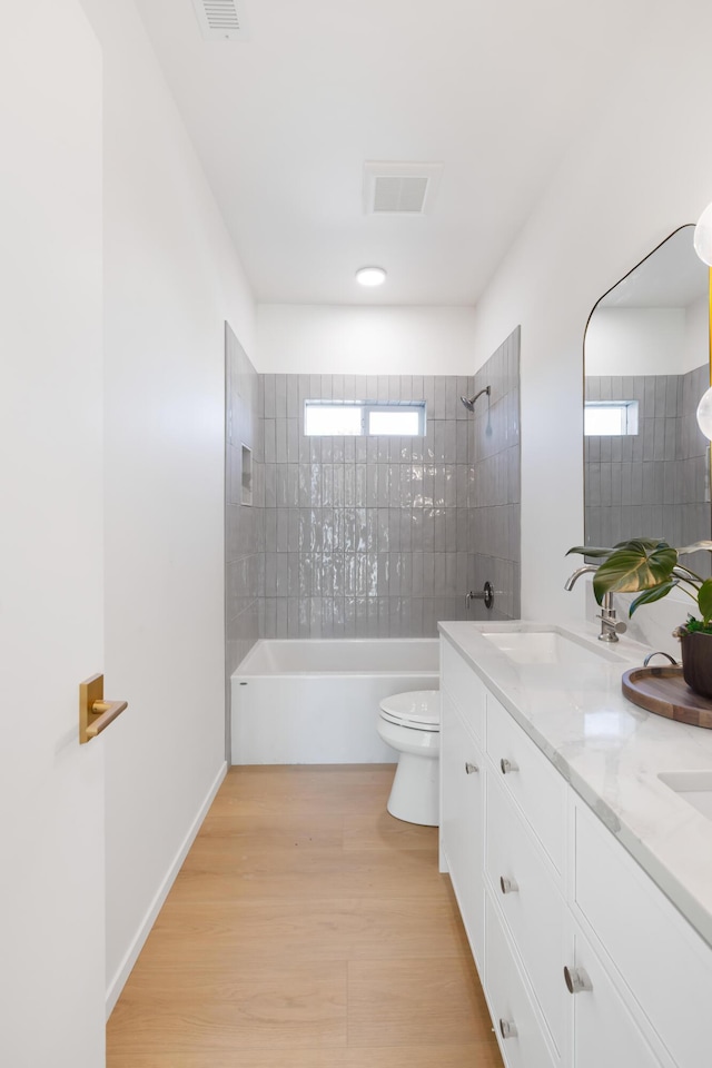 full bathroom with wood finished floors, double vanity, toilet, visible vents, and bathing tub / shower combination