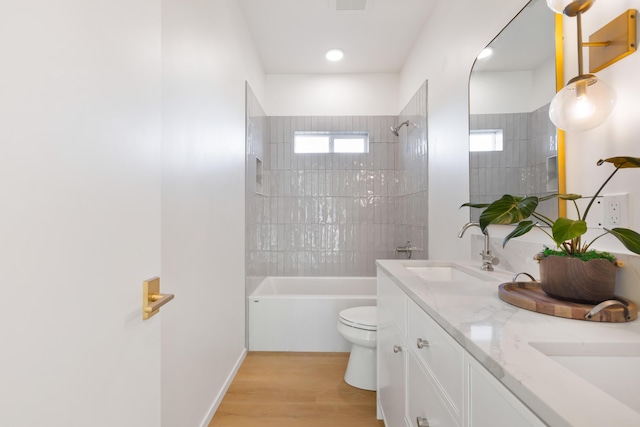 full bath featuring a sink,  shower combination, double vanity, toilet, and wood finished floors