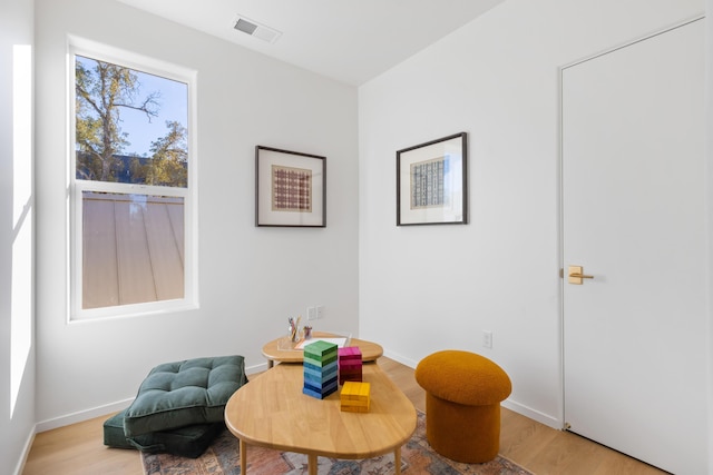 living area featuring light wood finished floors, baseboards, and visible vents