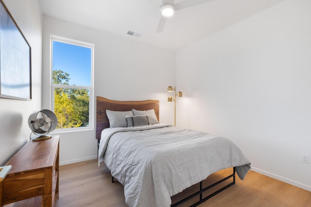 bedroom with wood finished floors, visible vents, a ceiling fan, and baseboards