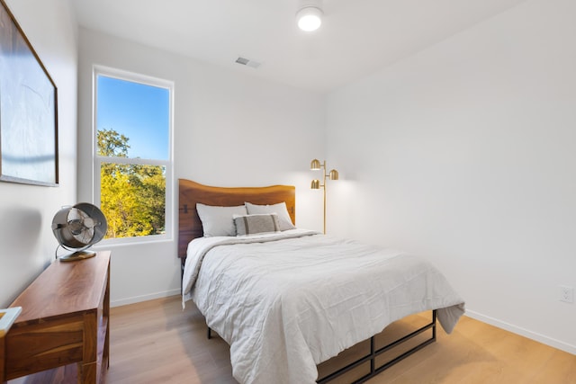 bedroom with baseboards, wood finished floors, and visible vents