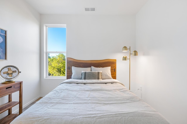 bedroom featuring wood finished floors, visible vents, baseboards, and multiple windows