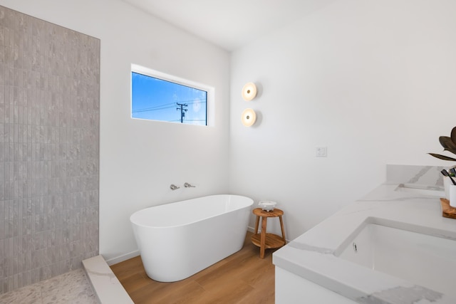 bathroom featuring a soaking tub, wood finished floors, a sink, and tiled shower