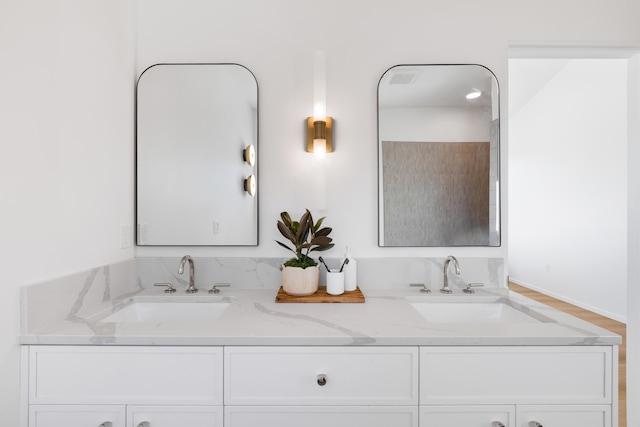 full bath featuring wood finished floors, a sink, and double vanity