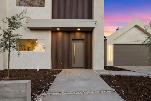 exterior entry at dusk featuring stucco siding