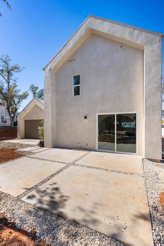 back of property with stucco siding and a patio area