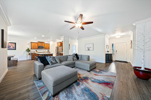 living room featuring a ceiling fan, baseboards, ornamental molding, and dark wood finished floors
