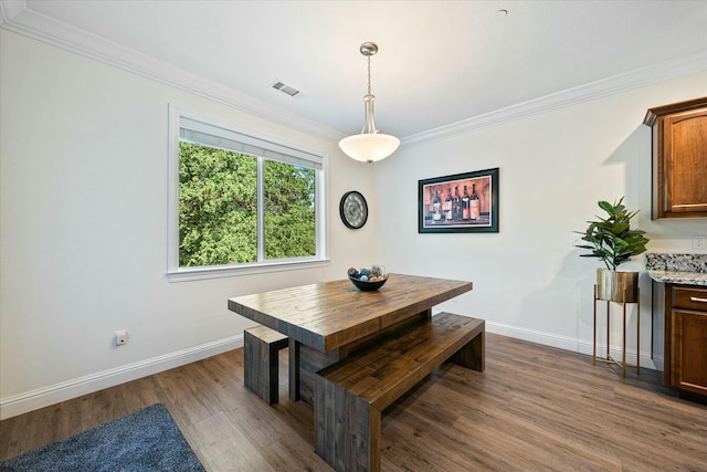 dining area with baseboards, visible vents, ornamental molding, and dark wood finished floors