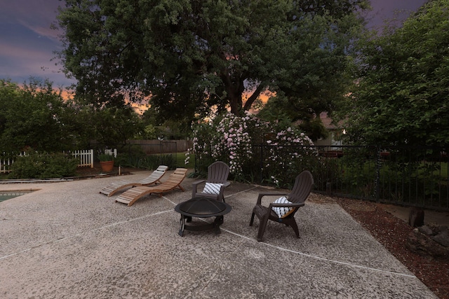 patio terrace at dusk featuring fence and an outdoor fire pit
