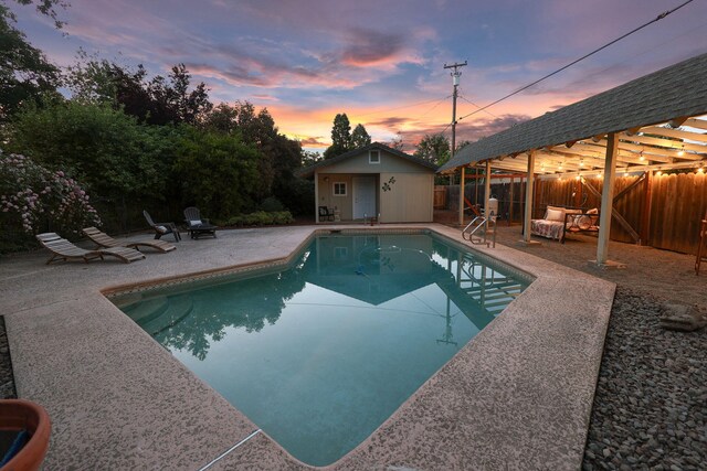 7057 Riata Dr, Redding, CA 96002 - pool at dusk featuring a gazebo, a patio, a fenced backyard, and an outbuilding