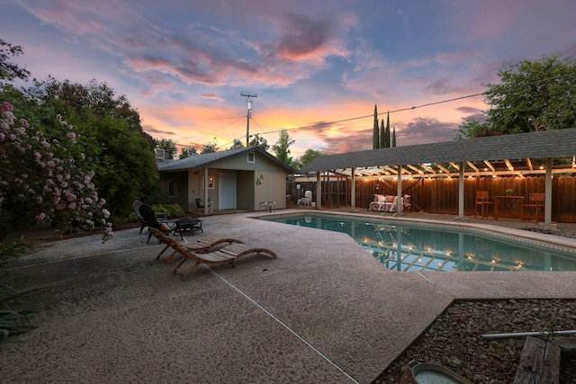 7057 Riata Dr, Redding, CA 96002 - pool at dusk with a patio area, fence, and an outbuilding