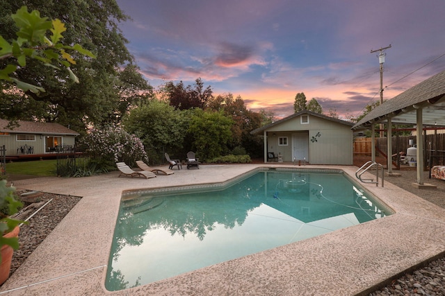 7057 Riata Dr, Redding, CA 96002 - pool at dusk with a patio, fence, and an outbuilding