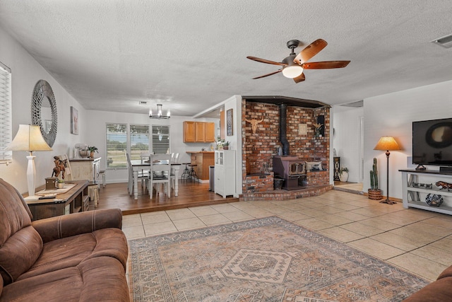 4647 County Road Ff, Orland, CA 95963 - living area featuring tile patterned flooring, ceiling fan, a textured ceiling, a wood stove, and a chandelier