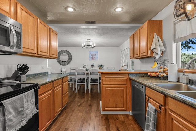 4647 County Road Ff, Orland, CA 95963 - kitchen with stainless steel appliances, dark countertops, dark wood-style floors, a sink, and a chandelier