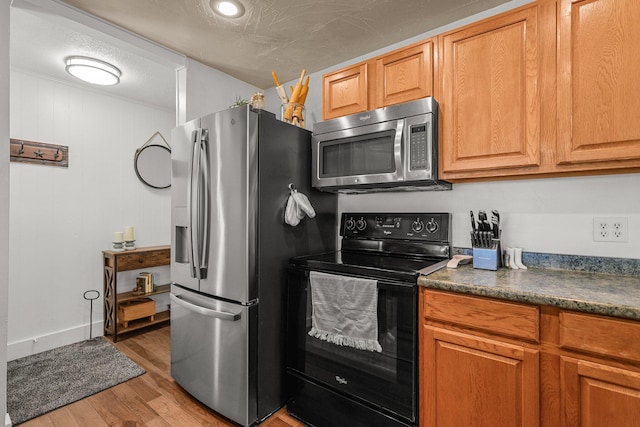 4647 County Road Ff, Orland, CA 95963 - kitchen with stainless steel appliances, light wood-type flooring, dark countertops, and brown cabinetry