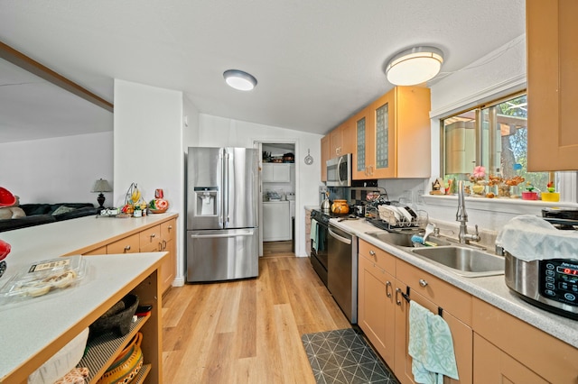 kitchen featuring vaulted ceiling, a sink, glass insert cabinets, stainless steel appliances, and light countertops