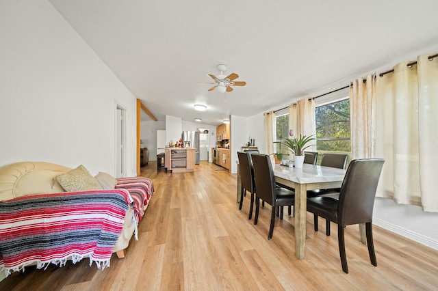 dining space featuring light wood-type flooring, a ceiling fan, and baseboards