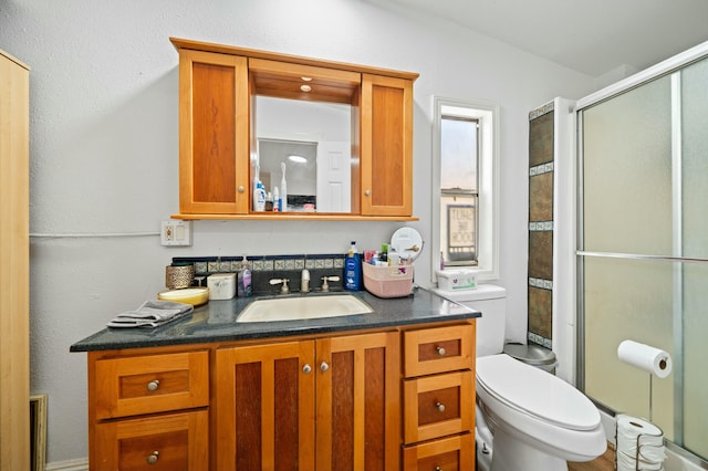 full bath with toilet, vanity, and a stall shower