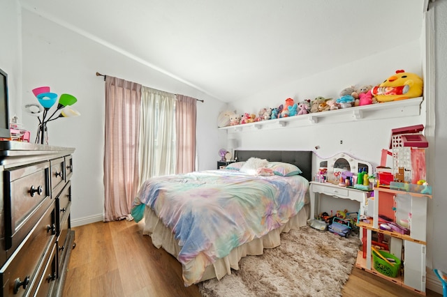 bedroom with vaulted ceiling, light wood-style floors, and baseboards