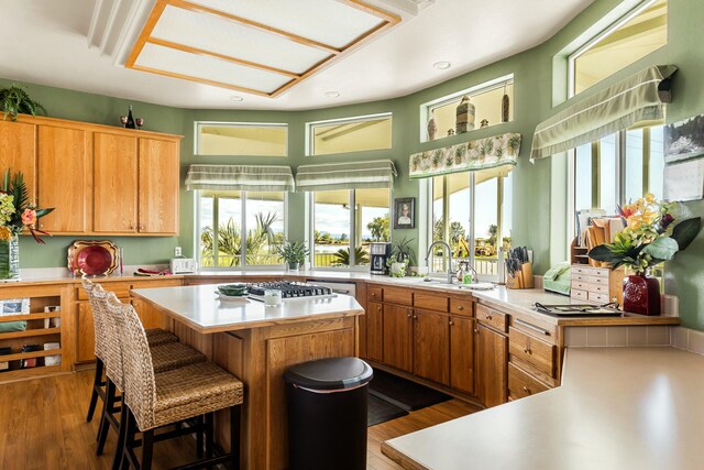 21623 Seven Lakes Ln, Redding, CA 96003 - kitchen with stainless steel gas cooktop, plenty of natural light, wood finished floors, light countertops, and a kitchen island