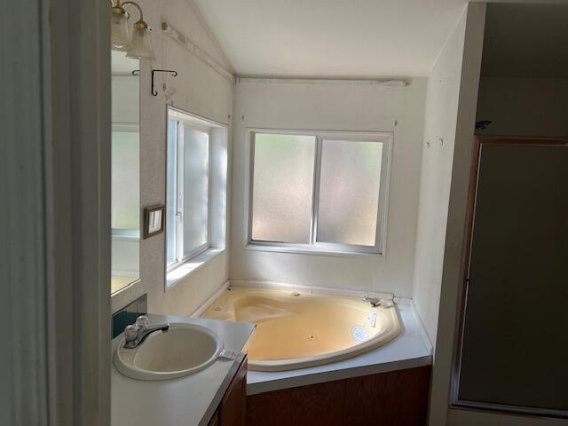 8725 Rocky Mountain Rd, Shingletown, CA 96088 - bathroom featuring a garden tub, vanity, and vaulted ceiling