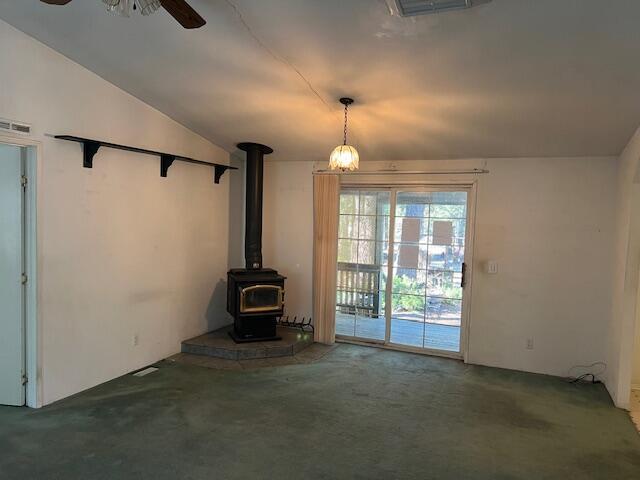 8725 Rocky Mountain Rd, Shingletown, CA 96088 - unfurnished living room with carpet, lofted ceiling, a wood stove, visible vents, and ceiling fan