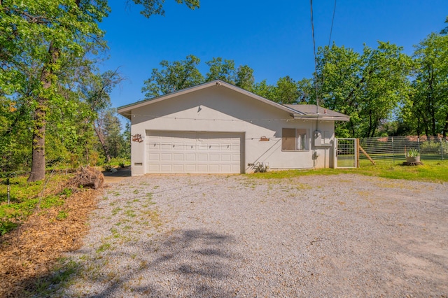 view of front of house featuring stucco siding, an attached garage, driveway, and fence
