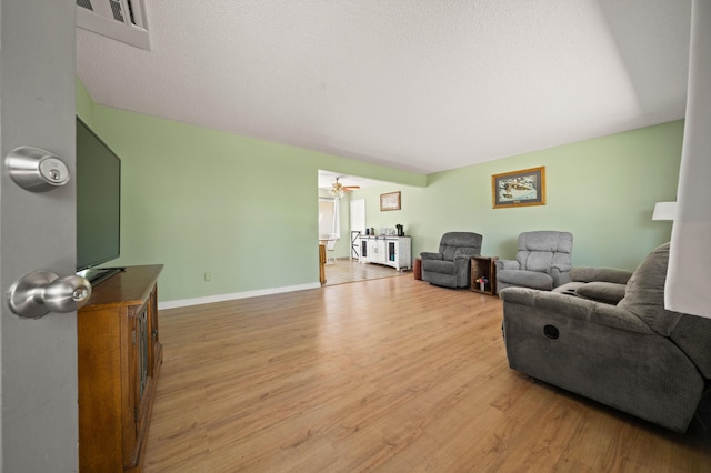 living room with light wood-style floors, baseboards, and ceiling fan
