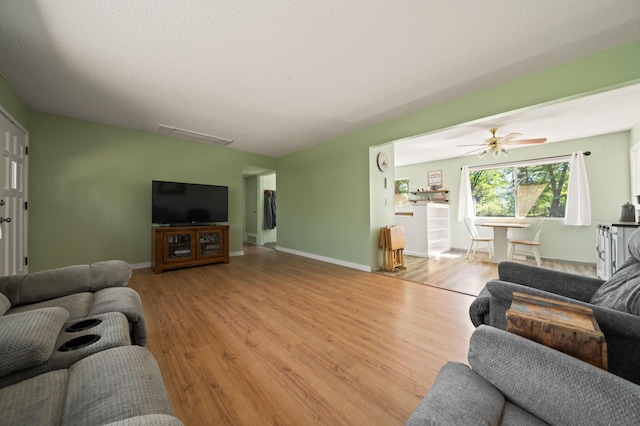 living area with baseboards, a ceiling fan, and light wood-type flooring
