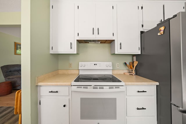 kitchen featuring white range with electric cooktop, under cabinet range hood, light countertops, white cabinetry, and freestanding refrigerator