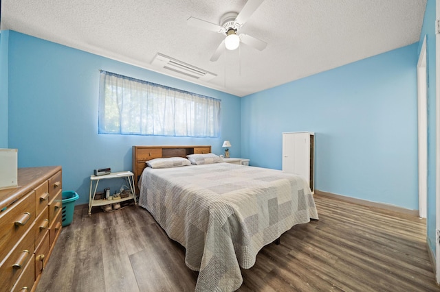 bedroom with baseboards, a ceiling fan, dark wood-style floors, and a textured ceiling