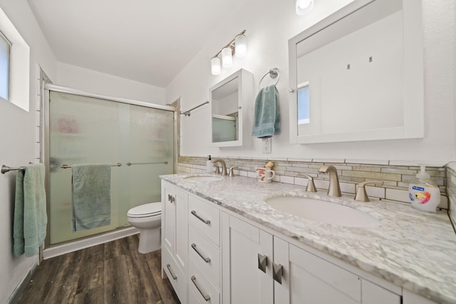bathroom featuring double vanity, wood finished floors, a stall shower, and a sink
