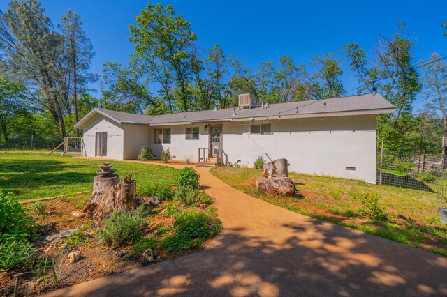 rear view of property featuring stucco siding, a yard, crawl space, and fence