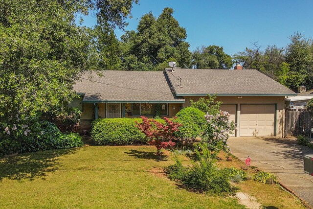 ranch-style home with fence, a shingled roof, a front lawn, concrete driveway, and an attached garage