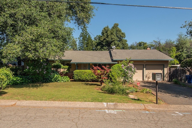 ranch-style home featuring a garage, driveway, a front lawn, and fence