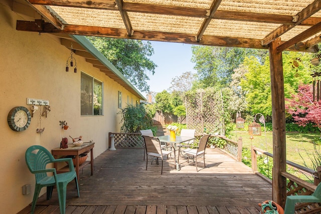 deck featuring outdoor dining area, fence, and a lawn