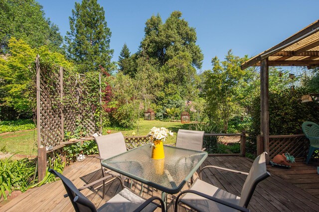 wooden terrace featuring a lawn and outdoor dining area